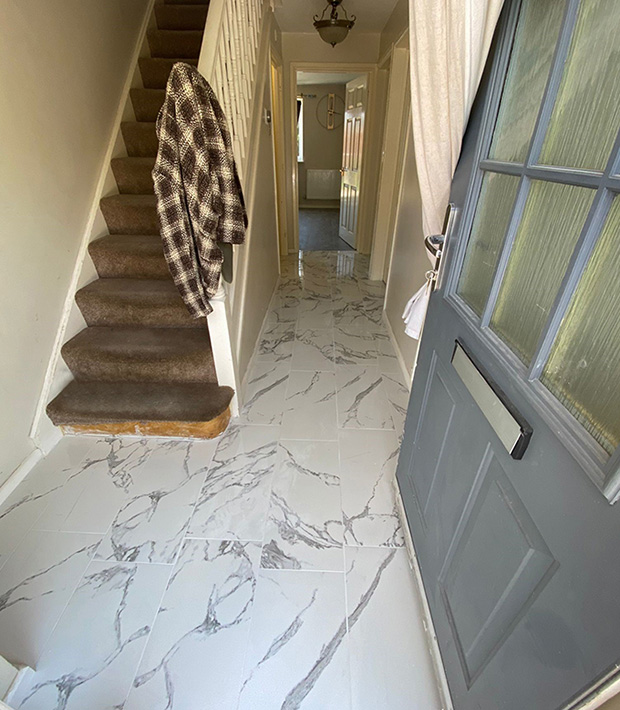 the entrance hallway of a home with a staircase to the left and a marble tiled floor